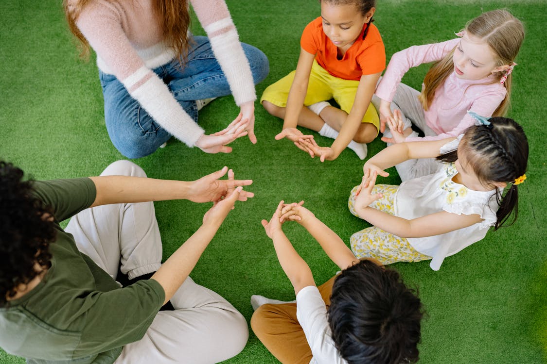 Teacher and children doing hand exercises on grass